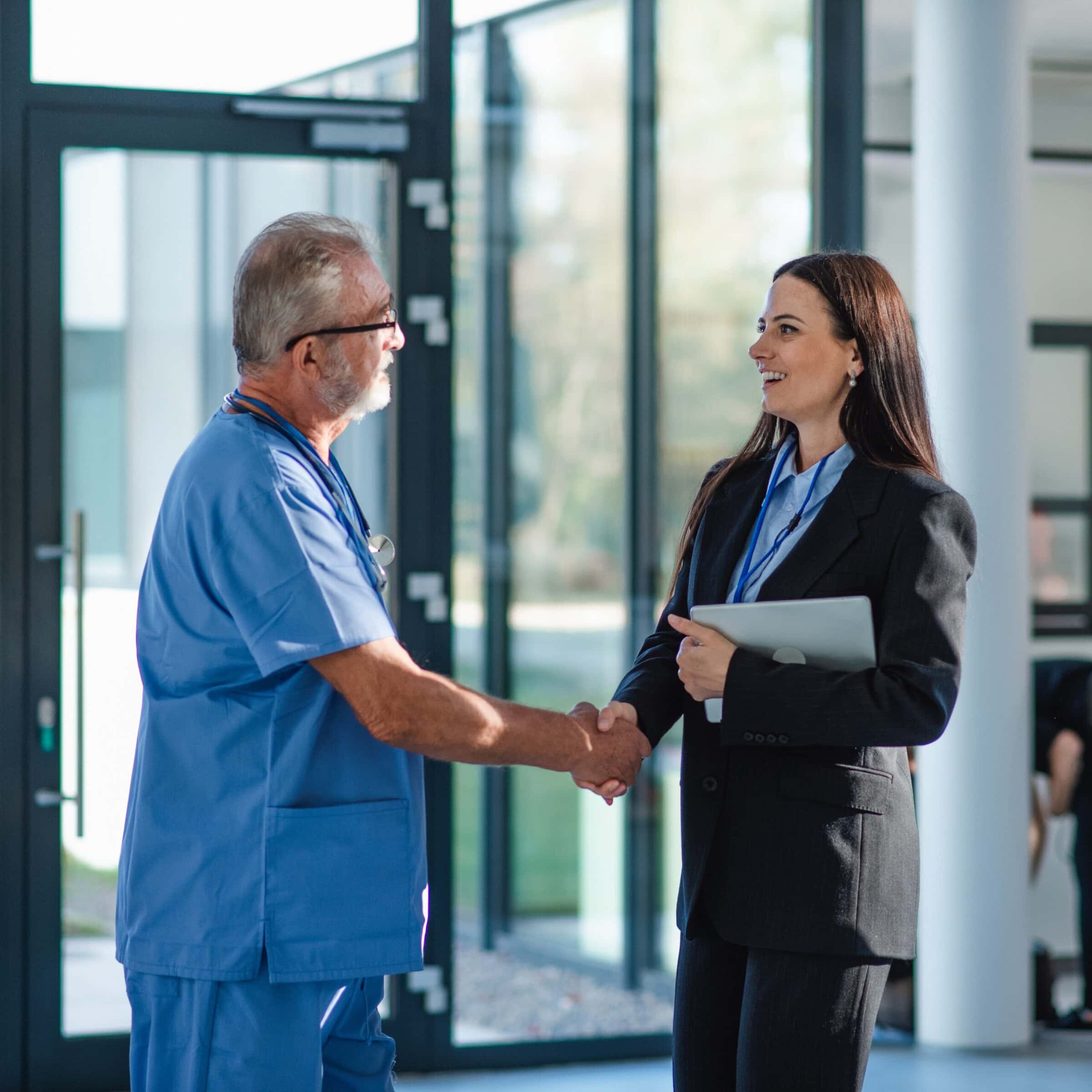 Young business woman shaking hand with elderly doctor.
